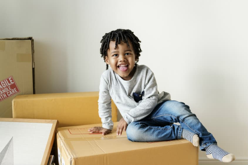young boy smiling on moving boxes