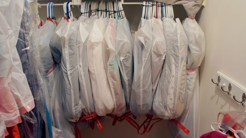 clothing on hangers packed in garbage bags